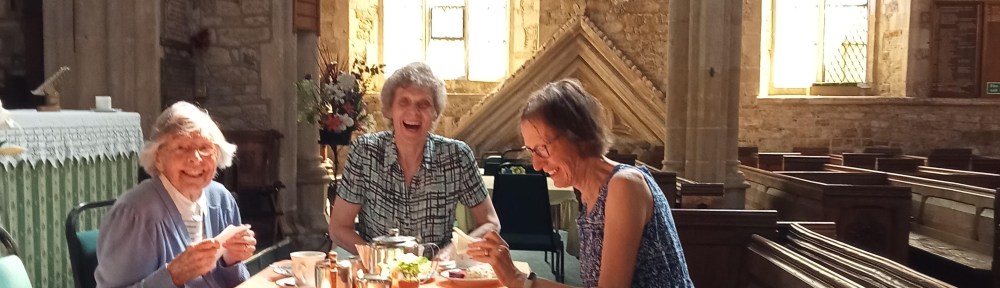 Enjoying a Cream Tea - The photo shows three lovely ladies enjoying a Cream Tea inside St Peter's Church. The three are sitting round a table with tea and scones and all smiling most happily